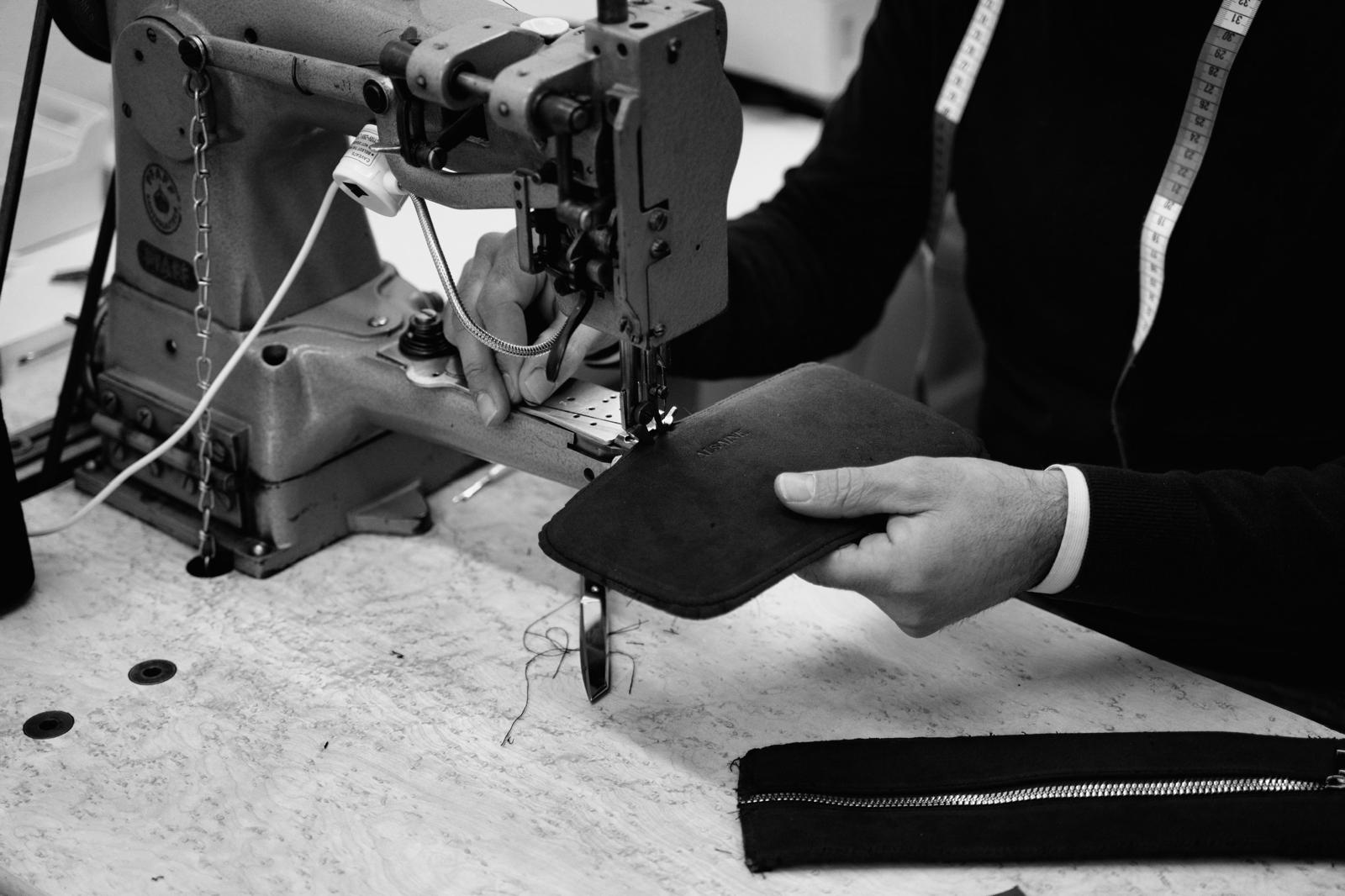 Handgemaakt: een vakman plaatst een Alsaine Alcantara toilettas onder de naaimachine tijdens het productieproces